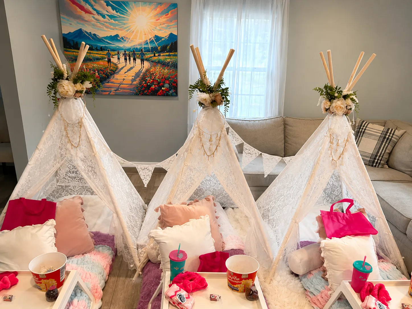 Three white lace teepee tents styled with fairy lights, floral crowns, and breakfast trays in a home living room