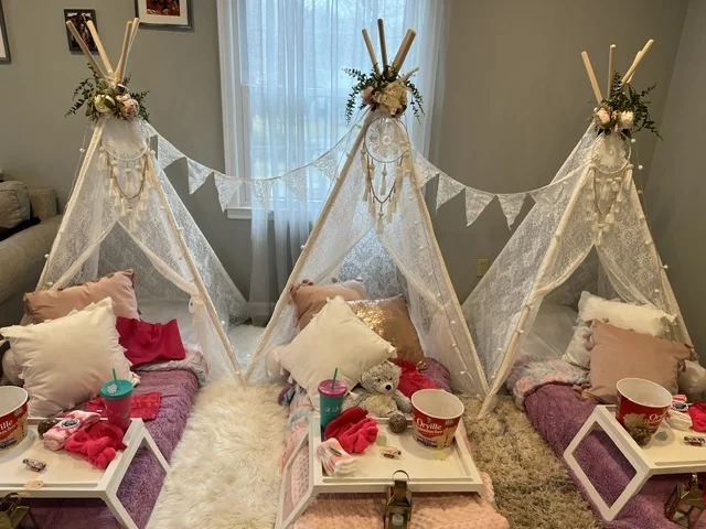 Intimate three-tent Posh & Pop sleepover setup with white teepees, lanterns, and plush bedding
